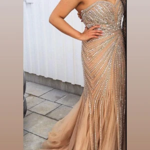 Champagnefärgad långklänning med paljetter - Säljer en magisk champagnefärgad långklänning med glittriga paljetter och pärlor i ett snyggt mönster. Klänningen är axelbandslös och har en v-ringad överdel som ger en elegant siluett. Perfekt för bal eller bröllop du kommer verkligen sticka ut! Märket terani couture i storlek 40 men går att sy in. Inköpspris 9500 säljer för 3500 pris kan diskuteras. Finns i Göteborg och Jönköping för upphämtning. 