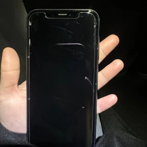 iPhone XR 64GB - Säljer en svart iPhone XR med 64GB lagring. Telefonen har synliga sprickor på både fram- och baksidan samt märken på ramen, men fungerar med iOS 18.2.1 installerat. Perfekt som reservtelefon eller för den som vill ha en prisvärd iPhone.