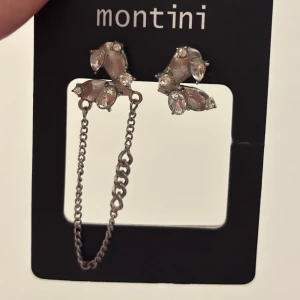 Silverfärgade örhängen med kedja  - Snygga silverfärgade örhängen med glittrande stenar och en cool kedjedetalj som kopplar ihop örhängena. 