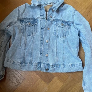 Ljusblå jeansjacka från 157, stl M - Supersnygg klassisk ljusblå jeansjacka från 157 i storlek M. Jackan har knappar framtill, två bröstfickor med lock och knapp samt en rak, lite croppad passform. Perfekt att slänga över en t-shirt eller hoodie för en chill look. Superbra för att lyfta en outfit! Jackan är knappt använd. Orginalpriset är 400kr.  Skriv gärna om intresserad, kan ändra priset. 💕💕