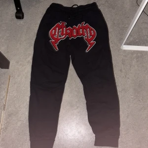 Svarta mjukisbyxor FSBN med röd text - Svarta mjukisbyxor från FSBN i storlek M med resår i midjan och snörning. På framsidan finns en stor röd och vit broderad text med ordet 'chaotic' i en cool stil. Byxorna har mudd vid benslut och en bakficka.