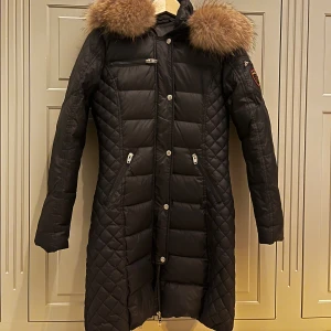 ROCKANDBLUE SWEDEN VINTER KAPPA - Rockandblue sweden svart lång vinter kappa storlek 34 i svart. En fluffig luva och många fickor. Den har ett blixtlås mitt i och sedan knappar, ärmarna har också blixtlås på armarna 