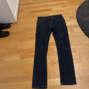 Mörkblå jeans från Nudie Jeans Co W28 L32 - Säljer ett par oanvända (men prövade) jeans från nudie. Modell:Lean Dean. Orginalpris:1600 kr. De är uppsydda till storlek 30. Säljer på grund av att de är lite för tajta för min smak.