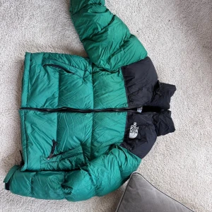 Grön och svart pufferjacka North Face XS - Säljer en grön och svart pufferjacka från The North Face i storlek XS. Jackan har dunfyllning, dragkedja framtill och två sidofickor med dragkedja. Perfekt för kalla dagar och har en riktigt chill streetstil. Logga på bröstet och ryggen.