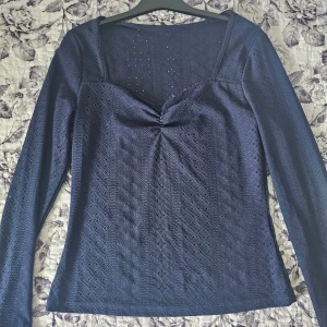Mörkblå långärmad spetsblus - Säljer en mörkblå långärmad blus med spetsdetaljer och v-ringad hals. Köpt för 299 kr