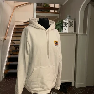 Vit hoodie  - Säljer en vit hoodie med stor huva. Framsidan har en liten logga på bröstet och baksidan har ett stort motiv med racingbil och texten 'Stopping Power'. Hoodien har känguruficka. Perfekt för dig som gillar bilar eller motorer.