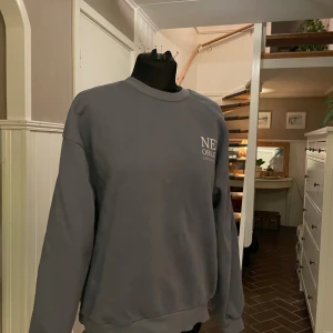 Grå sweatshirt  - En enkel och stilren grå sweatshirt med New Orleans tryckt på bröstet. Tröjan har rund hals, långa ärmar och en loose passform som gör den skön att bära. Perfekt för chill dagar och passar till jeans eller mjukisbyxor.