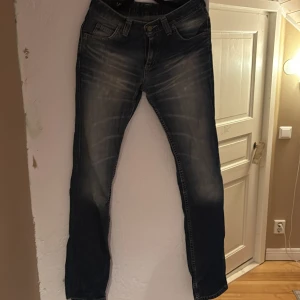 Mörkblå Lee jeans med slitningar - Snygga mörkblå jeans från Lee med klassisk femficksdesign och tydliga slitningar framtill. Jeansen har raka ben och en något tvättad look som ger en cool vibe. Perfekta för dig som gillar en avslappnad stil med lite edge.
