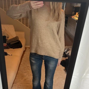 Beige stickad tröja med v-ringning - Mysig beige stickad tröja med v-ringad hals och ribbade ärmar vid ärmslut och nederkant, perfekt till hösten 🍁Enkel och stilren design som är lätt att matcha. Storlek S men passar både XS och M beroende på hur man vill att den ska sitta 🫶🏼