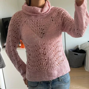 Rosa stickad  - Superfin rosa stickad polotröja med snyggt hålmönster och lång ärm. Tröjan har en lös polokrage och är stickad i ett luftigt garn som ger en cool och feminin look. Perfekt att styla med jeans eller kjol för en trendig outfit.