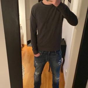 Mörkgrå tröja från Jack & Jones - Säljer en stilren mörkgrå tröja från Jack & Jones i storlek S. Tröjan har rund halsringning och långa ärmar, perfekt för lager-på-lager. Enkel och clean design som funkar till det mesta. 