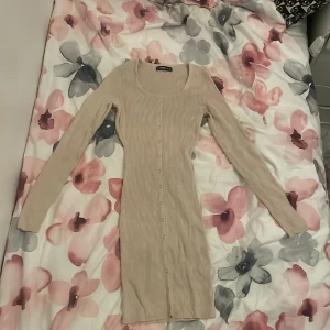 Beige ribbad långärmad klänning - Supersnygg beige ribbad klänning med lång ärm och knappar hela vägen framtill. Den har en tight passform. 