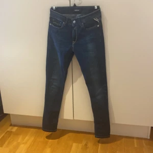 Mörkblå Replay New Luz jeans - Snygga mörkblå jeans från Replay, modell New Luz. Jeansen har klassisk femficksdesign, kontrastsömmar och raka ben. Materialet är stretchigt jeans för en bekväm passform. Perfekta för dig som gillar stilrena och tidlösa jeans.