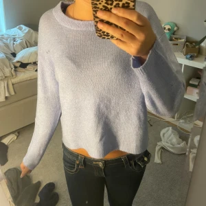 Ljuslila stickad croppad tröja - Superfin ljuslila stickad tröja med croppad passform och rund halsringning. Tröjan har långa ärmar och är perfekt för dig som gillar en enkel men trendig look. Mjuk och skön att bära, passar perfekt till jeans eller kjol.