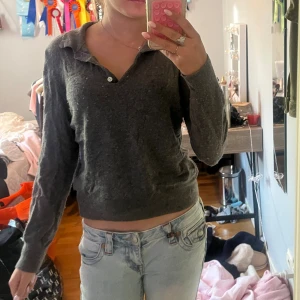 Mörkgrå långärmad pikétröja Zara - Mörkgrå pikétröja från Zara i mjukt material. Tröjan har klassisk krage, knappar vid halsen och lång ärm. Enkel och stilren modell som är lätt att matcha till jeans eller kjol.