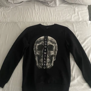 Svart sweatshirt SMDG med döskalle - Svart sweatshirt från SMDG i regular fit med stort döskalletryck framtill och texten 'ICONO MILANO' i mitten. Knappt använd