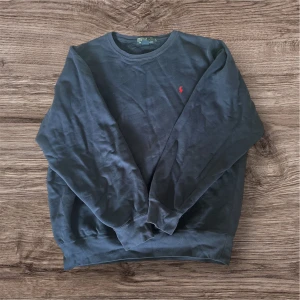 Mörkblå sweatshirt från Polo Ralph Lauren - Klassisk mörkblå sweatshirt från Polo Ralph Lauren med rund hals och röd broderad logga på bröstet. Tröjan är i mycket bra skick utan defekter. Skriv vid frågor!