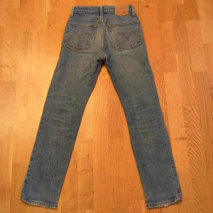 Levi's 501 blå jeans straight fit - Klassiska Levi's 501 jeans i blå denim med raka ben och knäppning med knappar. Snyggt slitna detaljer och ikonisk läderpatch bak i midjan. Jeansen har fem fickor och orange sömmar. Perfekta för en avslappnad och tidlös stil. Har ett par mörkgrå, ett par ljusgrå och ett par ljusblå. Samma storlek modell och skick. 350:- st eller 800:- för alla tre