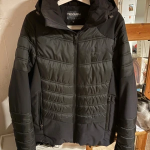 Svart pufferjacka från Tenson med huva - Säljer en svart jacka från Tenson. Snygg modell och fungerar för både höst och vinter. Den är varm och otroligt fin! 