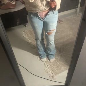 Ljusblå bootcut jeans med slitningar - Säljer ett par ljusblå jeans med bootcut passform och snygga slitningar på båda benen. Säljer då dom inte passar mig längre! Dom är från Lee.