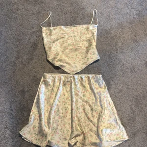 Blommigt satin set från Gina Tricot - Säljer ett blommigt set från Gina Tricot i satinliknande material. Kjolen är elastisk i midja och toppen går att justera!💕
