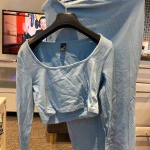 Ljusblå ribbad långärmad topp SHEIN - Ljusblå croppad topp från SHEIN med lång ärm och ribbad struktur. Toppen har en bred, rundad urringning och är tillverkad i ett mjukt stretchigt material som känns skönt mot huden. Perfekt att styla med höga jeans eller kjol.