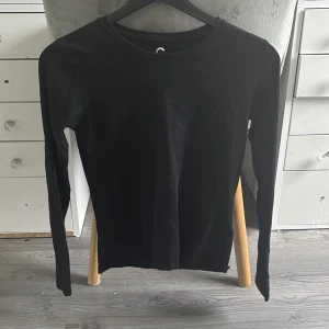 Svart långärmad basic tröja - En stilren svart långärmad tröja med rund halsringning. Perfekt som basplagg och enkel att matcha med olika outfits. Tillverkad i mjuk bomull för en skön känsla hela dagen.