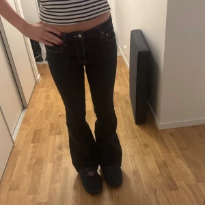 Svarta bootcut jeans  - Säljer ett par svarta jeans med bootcut-modell och klassiska kontrastsömmar. Jeansen har låg midja och fem fickor, tillverkade i ett robust denimtyg. Perfekta för dig som gillar en tidlös och snygg siluett.