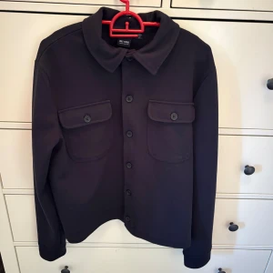 overshirt från Only & Sons - Marinblå overshirt från Only & Sons med klassisk krage och två stora bröstfickor med lock och knappar. Modellen har långa ärmar och knäppning framtill. Materialet är mjukt och känns som tjock bomull, perfekt för lager på lager. Snygg och enkel att styla till jeans eller chinos.