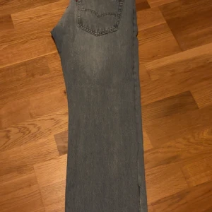 Levi's 501 blå jeans W31 L32 - Säljer ett par klassiska Levi's 501 jeans i blå tvätt. De har rak passform, femficksdesign och ikonisk läderpatch bak. Jeansen är i denim och har en snygg, något urtvättad look som passar till allt. Knappt använda 