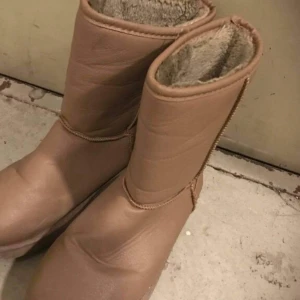 Beiga fodrade boots med platt sula - Mysiga beiga boots med mjukt foder på insidan och platt sula. Skorna har rund tå och är tillverkade i syntetmaterial med synliga sömmar. Perfekta för kalla dagar när du vill hålla fötterna varma och bekväma.