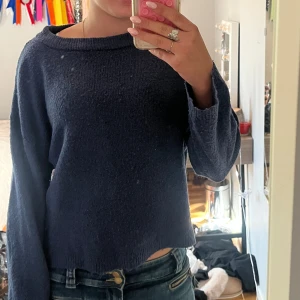 Mörkblå stickad tröja från 157 - Mysig mörkblå stickad tröja från 157 med avslappnad passform och bred halsringning. Tröjan har långa ärmar och är perfekt för lager-på-lager under kyliga dagar. Enkel och stilren design som funkar till jeans eller kjol.