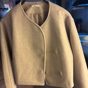 Beige kappa från Gina Tricot - beige kappa från Gina tricot med minimalistisk design och rundad halsringning. Jackan har dolda knappar framtill och är tillverkad i mjuk ullblandning. Perfekt för dig som gillar clean och modern look. Använd endast fåtal gånger superfint skick☺️