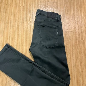 Replay Anbass svarta jeans, storlek 31 - Snygga svarta Replay Anbass jeans med klassisk femficksdesign och diskret logga på bakfickan. Jeansen har en rak passform och är tillverkade i mjukt bomullsmaterial med stretch för extra komfort. Perfekt för dig som gillar stilrena och tidlösa jeans.