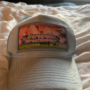 Ljusblå Djurgården keps Local Cap - Snygg ljusblå keps från Local Cap med mesh på sidorna och ett stort tryck framtill med Djurgårdens Idrottsförening. Perfekt för dig som vill visa vilket lag du håller på! Justerbar baktill för bästa passform.