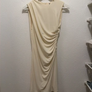 Champagnefärgad draperad klänning - Snygg ärmlös klänning i champagnefärg med draperad detalj längs sidan. Klänningen har en tight passform🩷 aldrig använd 💕