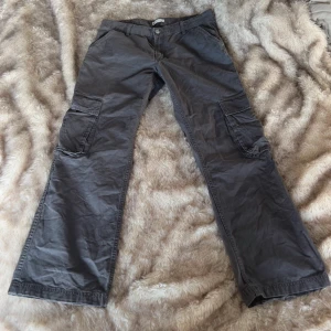 Grå cargobyxor från Gina Tricot - Snygga grå cargobyxor från Gina Tricot med raka ben och flera stora fickor på sidorna och bak. 