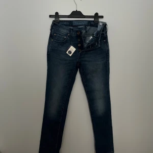 Jacob Cohën Premium Edition Buddy  - Snygga mörkblå jeans från Jacob Cohën Premium Edition med naturlig indigo-färgning och handgjorda detaljer. Modellen har raka ben, klassisk femficksdesign och knappar i guldton. Jeansen är tillverkade i mjukt bomullstyg med exklusiv känsla.