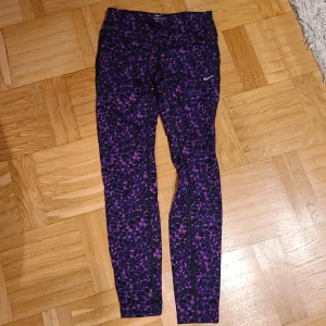 Nike Dri-Fit leopardmönstrade tights XS - Nike Dri-Fit tights i XS med lila och svarta leopardfläckar och inslag av rosa. Supersnygga och bekväma leggings i stretchigt funktionsmaterial, perfekta för träning. Hög midja och åtsittande passform. Swoosh-logga på benet.