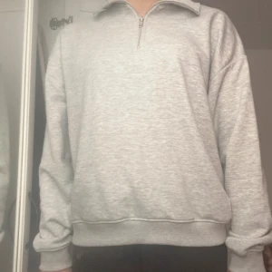 Grå half zip sweatshirt  - En stilren ljusgrå sweatshirt  med half zip och hög krage. Tröjan har lång ärm, ribbade muddar och är gjord i mjuk bomullsblandning, storlek M 