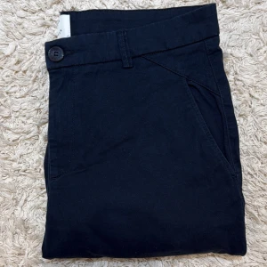 Mörkblå chinos - Snygga mörkblå chinos från Plain Units i klassisk rak modell. Nypris 1600kr mittpris 399 kr. Bra skick förutom att de har en liten fettfläcka som går att ta bort. Skriv vid frågor mvh!