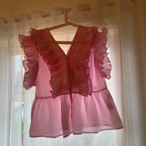 Rosa volangblus från Y.A.S - Supersöt rosa blus från Y.A.S i modellen YASRUNA med volanger framtill och på axlarna. Blusen har v-ringning, knappar framtill 