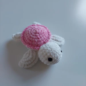 Virkad sköldpadda - Virkad sköldpadda i färger vit och rosa. Sköldpaddan är ca 20 cm lång 🩷