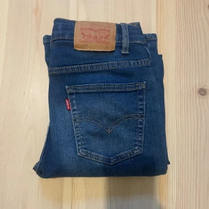 Levi's jeans - Snygga blå Levi's 502 Regular Taper jeans med klassisk femficksdesign och röd Levi's-tag på bakfickan. Jeansen har en avsmalnande passform och normal midja, tillverkade i mjukt denim med slitningar för en cool look. Hör av dig vid frågor!