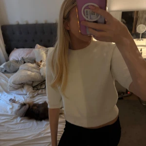 Vit stickad tröja från Zara - Säljer en vit stickad tröja från Zara i storlek L. Tröjan har rund hals, ribbade muddar och trekvartsärmar. Modellen är croppad och har en mjuk, mysig känsla som passar perfekt till jeans eller kjol. Enkel och stilren design.