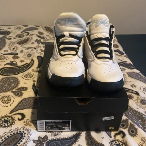 Jordan Max Aura 4 sneakers vit/blå - Säljer ett par Jordan Max Aura 4 sneakers i vitt med ljusblå detaljer och svart sula. Skorna har snörning, rund tå och coola kontraster mellan färgerna. Perfekta för dig som gillar streetwear och vill sticka ut med en sportig vibe.