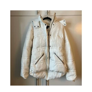 varm puffjacka i vitt med svarta detaljer storlek XS  - Stilren och varm puffjacka i vitt med svarta detaljer. Jackan har hög krage, dragkedja framtill med knappar för extra skydd mot kyla samt två praktiska fickor med dragkedja. Perfekt för vintern eller kyliga höstdagar!  ✅ Storlek: XS ✅ Färg: Vit med svarta detaljer ✅ Mycket bra skick,