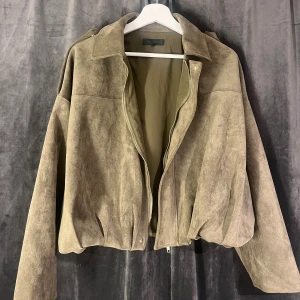 Grön  mockajacka från Zara - Snygg mockajacka från Zara med loose passform och dragkedja framtill. Jackan har klassisk krage, långa ärmar och en lätt croppad siluett. Perfekt för dig som gillar stilren och trendig look.