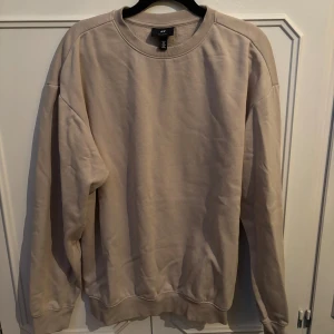 Beige och vit sweatshirt från H&M - Två stilrena sweatshirts från H&M i relaxed fit, en i beige och en i vitt. Båda har rund halsringning, långa ärmar och ribbade muddar. Perfekta för en chill och enkel look. Tillverkade i mjuk bomullsmix för extra komfort. Tröjorna var förstora och skickade aldrig tillbaka så de har legat i min garderob sedan dess, inprincip helt oanvända!