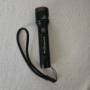 Ledlenser P5R Core - Kraftfull Ledlenser P5R Core ficklampa i mycket gott skick. Robust aluminiumkropp, uppladdningsbar via magnetkontakt, med handledsrem. Inga synliga repor eller skador. Perfekt för utomhusbruk, camping eller arbete.